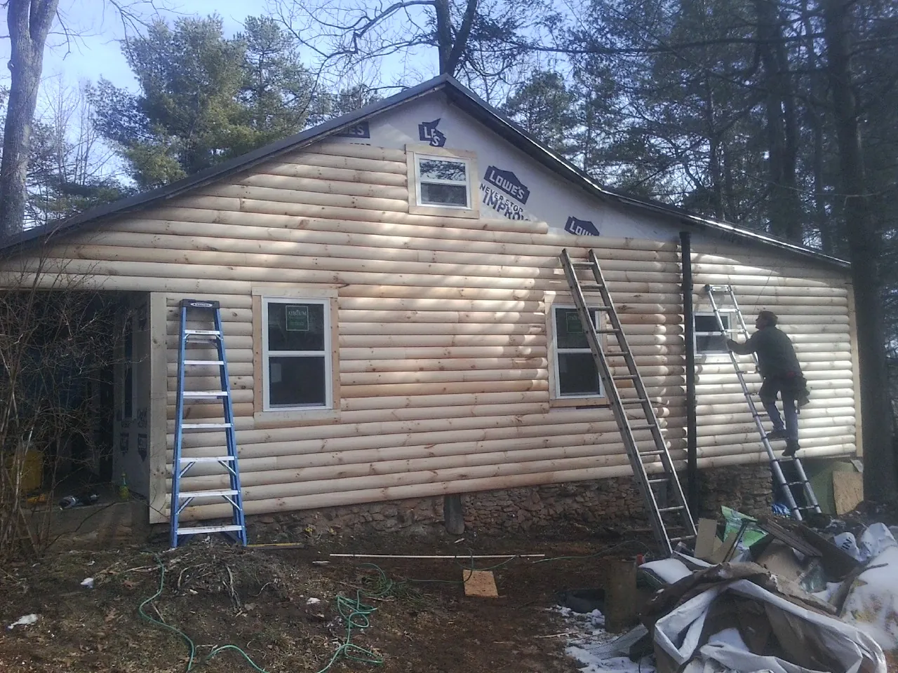 Ladders set against fresh log siding during an exterior remodel in Dexter